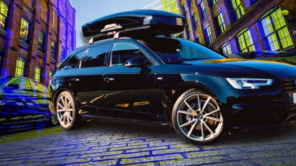 THULE MOTION XT CARGO BOX ON TOP OF MY BLACK AUDI A3 ON STREET WITH OTHER CARGO CARRIERS AT THE REAR OF THE CAR