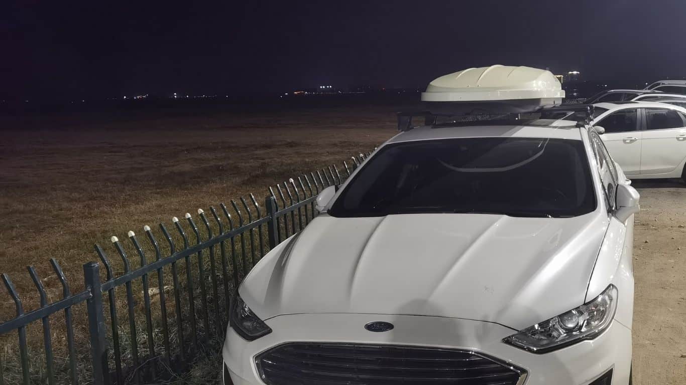 white car rooftop cargo carrier on Ford sedan along the beach