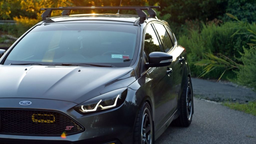 siliver Ford compact sedan has a pair of black square roof racks on its roof