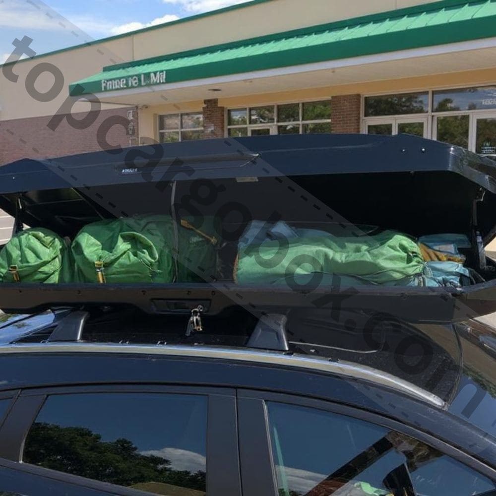 Camping gear like tents, sleeping bags, and foldable chairs neatly packed inside a roof cargo box, freeing up car space.
