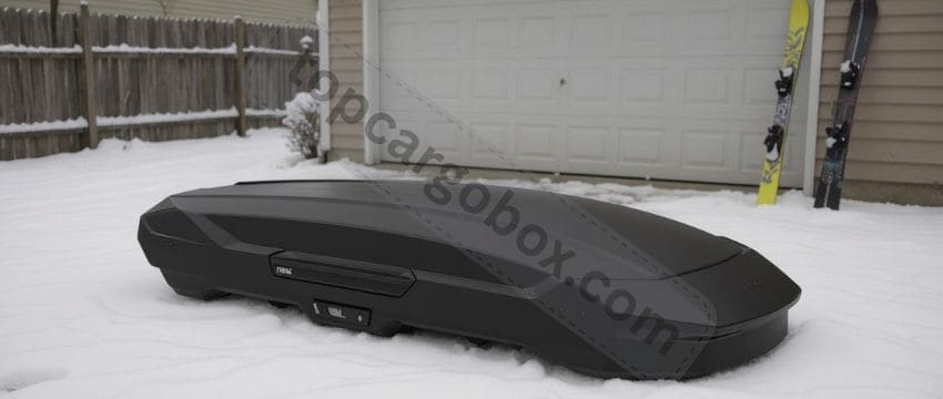 "Thule Motion 3 XL Low cargo box in dark gray, featuring aerodynamic curves and a wing-shaped profile for reduced wind resistance."